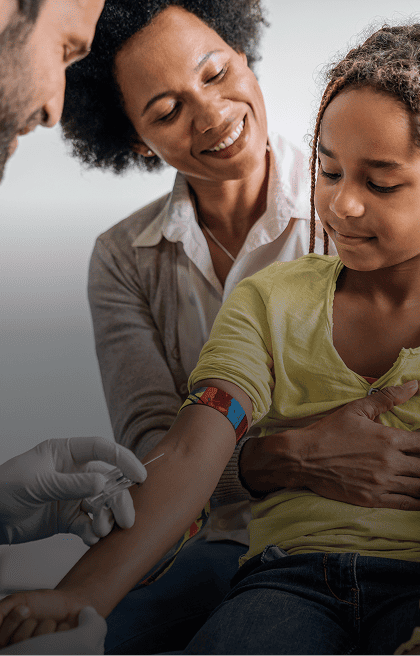 Médico retirando sangue de um paciente criança no colo de sua mãe